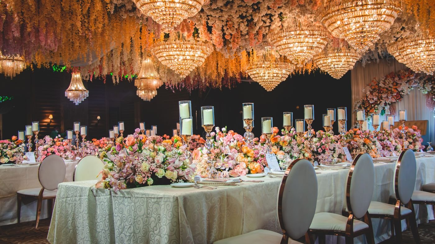 Feestelijk gedekte tafel met bloemen en kaarsen onder kroonluchters in een turkse bruiloft zaal